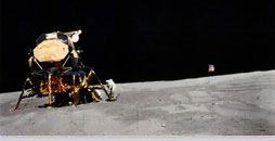 Charlie Duke at the steps of the Apollo 16 Lunar Module &ldquo;Orion&rdquo; with the US flag in the background.